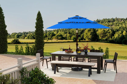 Outdoor patio set with table, chairs, and umbrella on a deck with a scenic background.