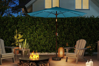 Outdoor patio setup with fire pit, chairs, and blue umbrella at night.