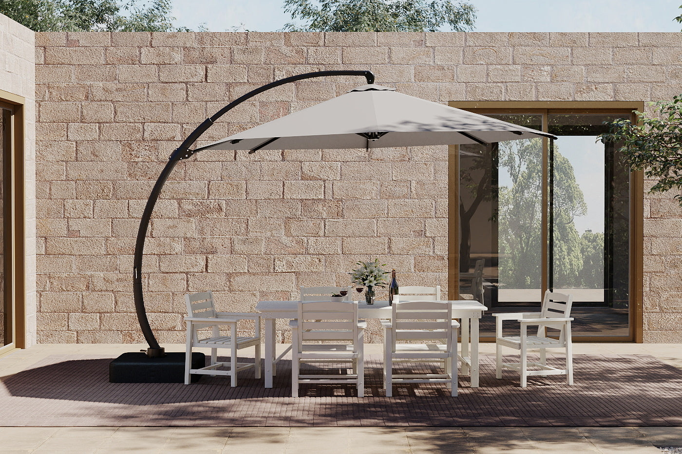 Outdoor patio set with table and chairs under a large patio umbrella against a stone wall.