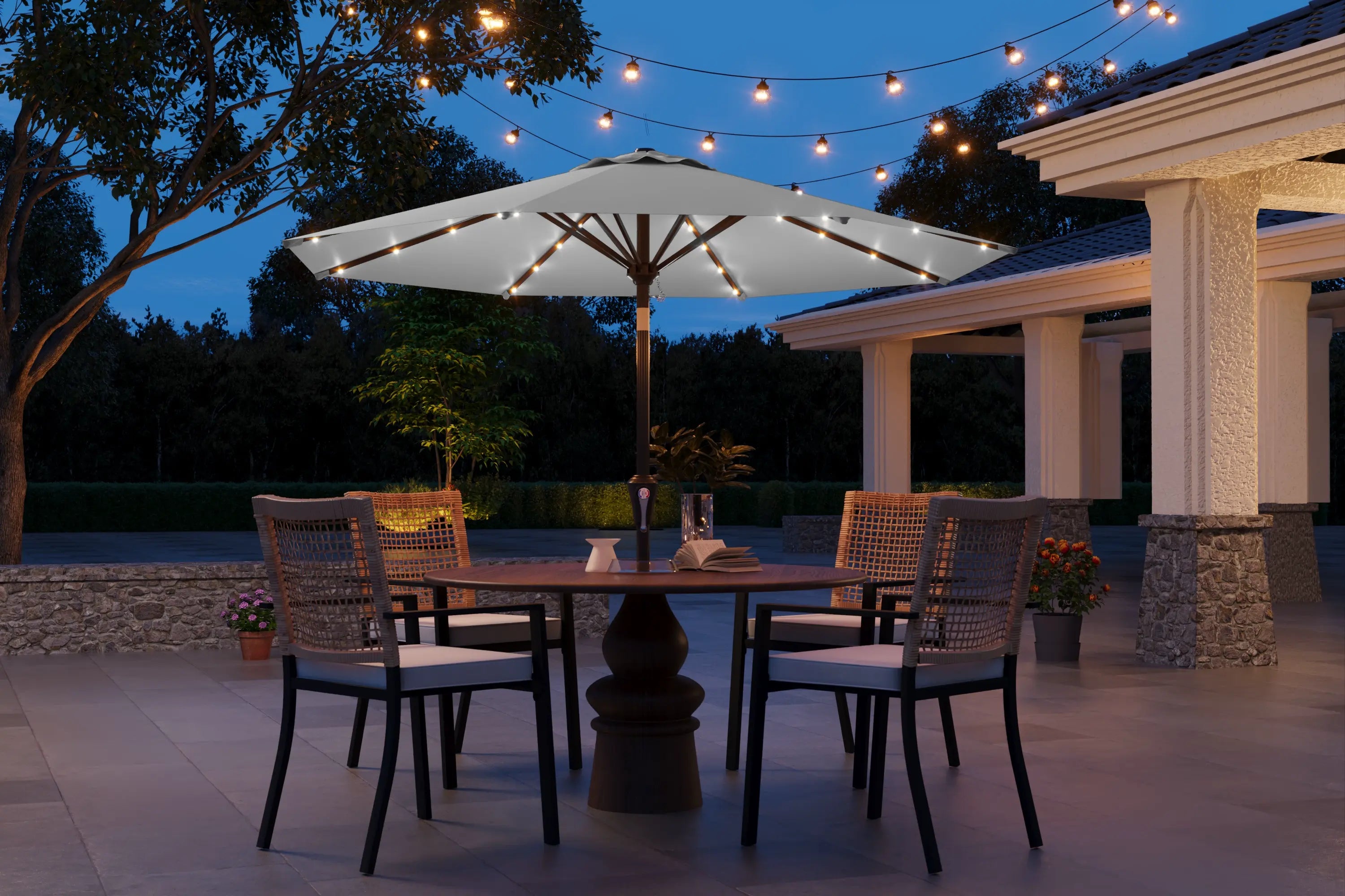 Outdoor patio setting with a table, chairs, and string lights under a large umbrella.