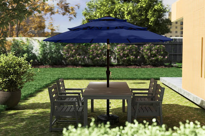 Outdoor patio set with table and chairs under a large blue umbrella in a garden setting.
