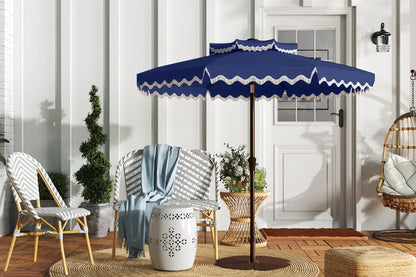 Blue outdoor umbrella with white trim on a patio with chairs and decor.