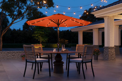 Outdoor patio setting with a table, chairs, and string lights under an umbrella at dusk.