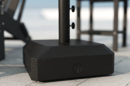 Black outdoor umbrella base on a patio with blurred background