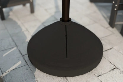 Black patio umbrella base on a stone pavement