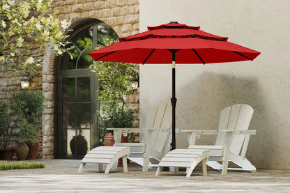 Red patio umbrella over white Adirondack chairs on a patio with a stone wall and door in the background.