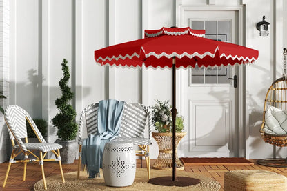 Red outdoor umbrella with white trim on a patio with chairs and decor.