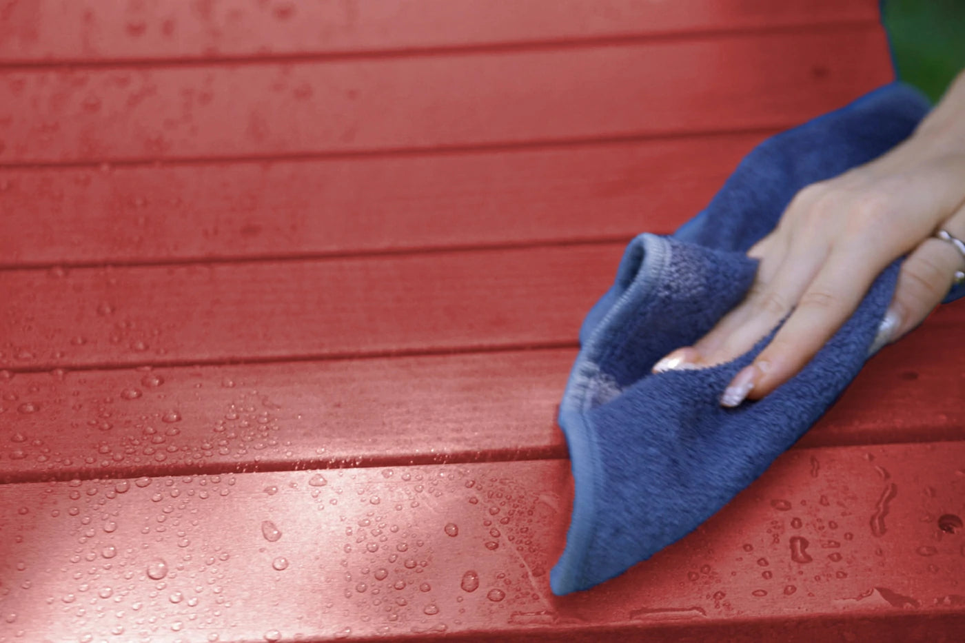 Person cleaning a red surface with a blue cloth