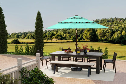 Outdoor patio set with table, chairs, and umbrella on a deck with a scenic background.