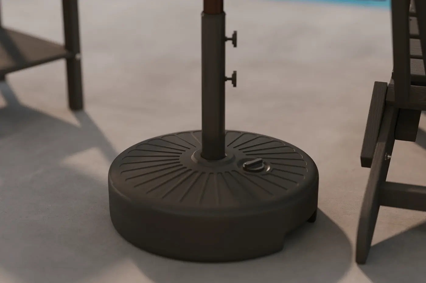 Black patio umbrella base on a concrete surface with chairs in the background