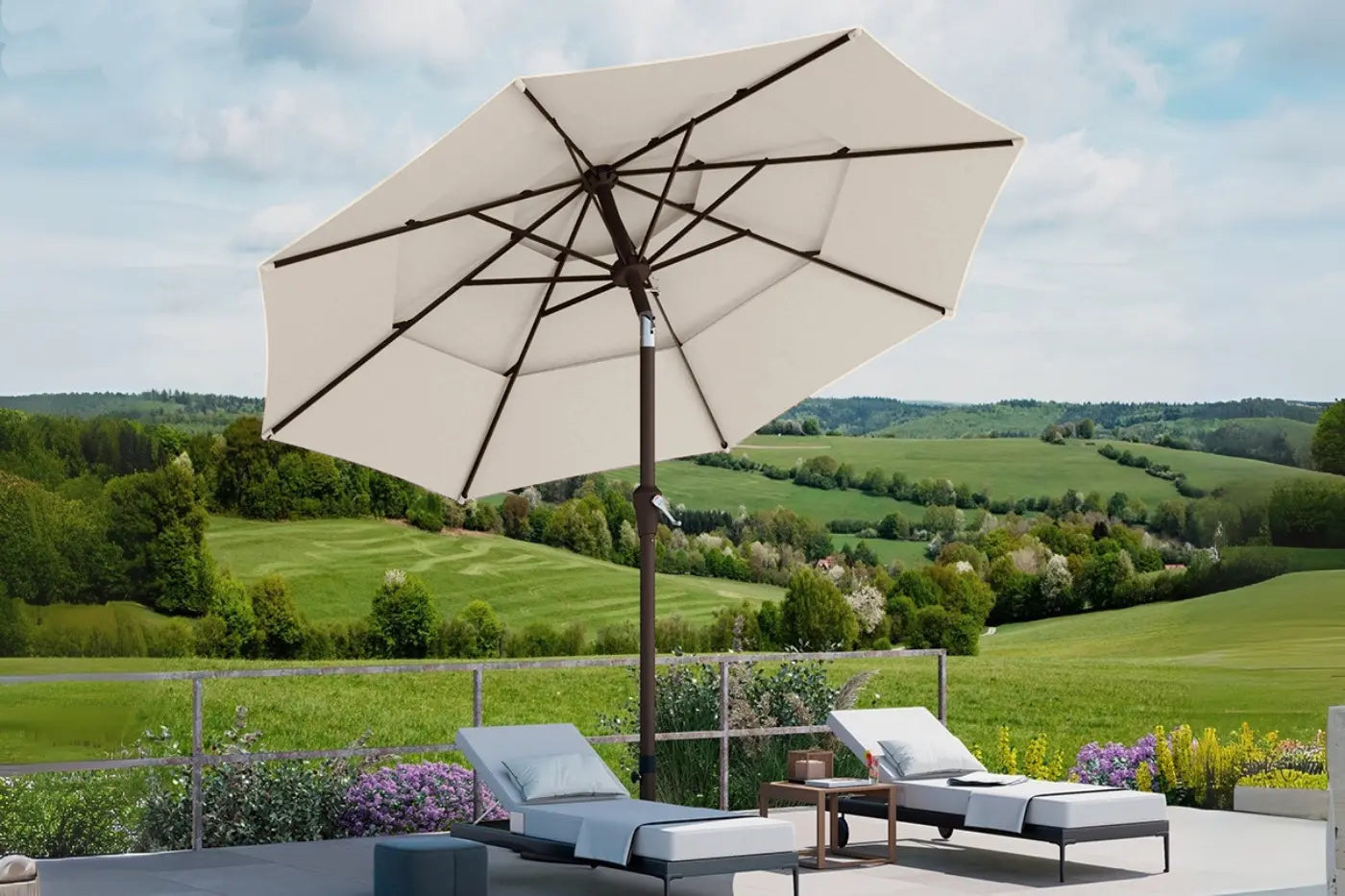 Beige patio umbrella with lounge chairs and a scenic view of green fields and hills.