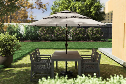 Outdoor patio set with table and chairs under a large umbrella on a grassy area.