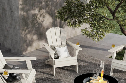 White Adirondack chairs around a fire pit with a tree and concrete wall in the background