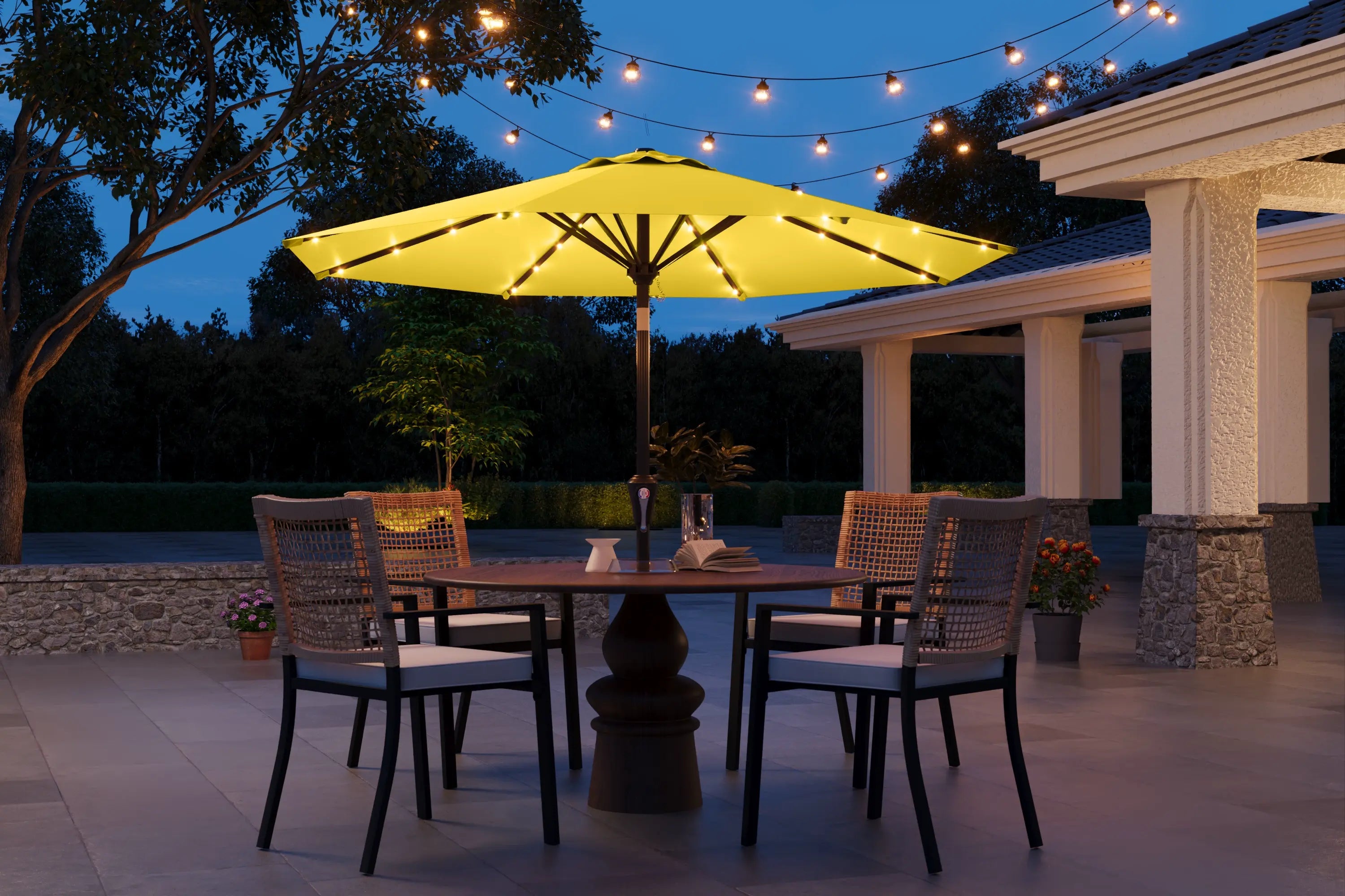 Outdoor patio set with a yellow umbrella and string lights at night.