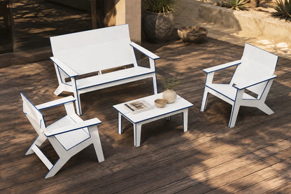A four-piece outdoor patio furniture set including a loveseat, two armchairs, and a small coffee table, all in white with thin blue trim, arranged on a wooden deck.