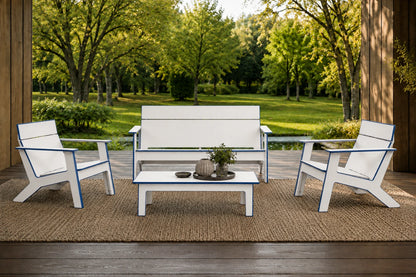 A 4-piece outdoor patio furniture set including a loveseat, two armchairs, and a coffee table, all in white with blue trim, arranged on a jute rug on a wooden deck with a lush green garden background.