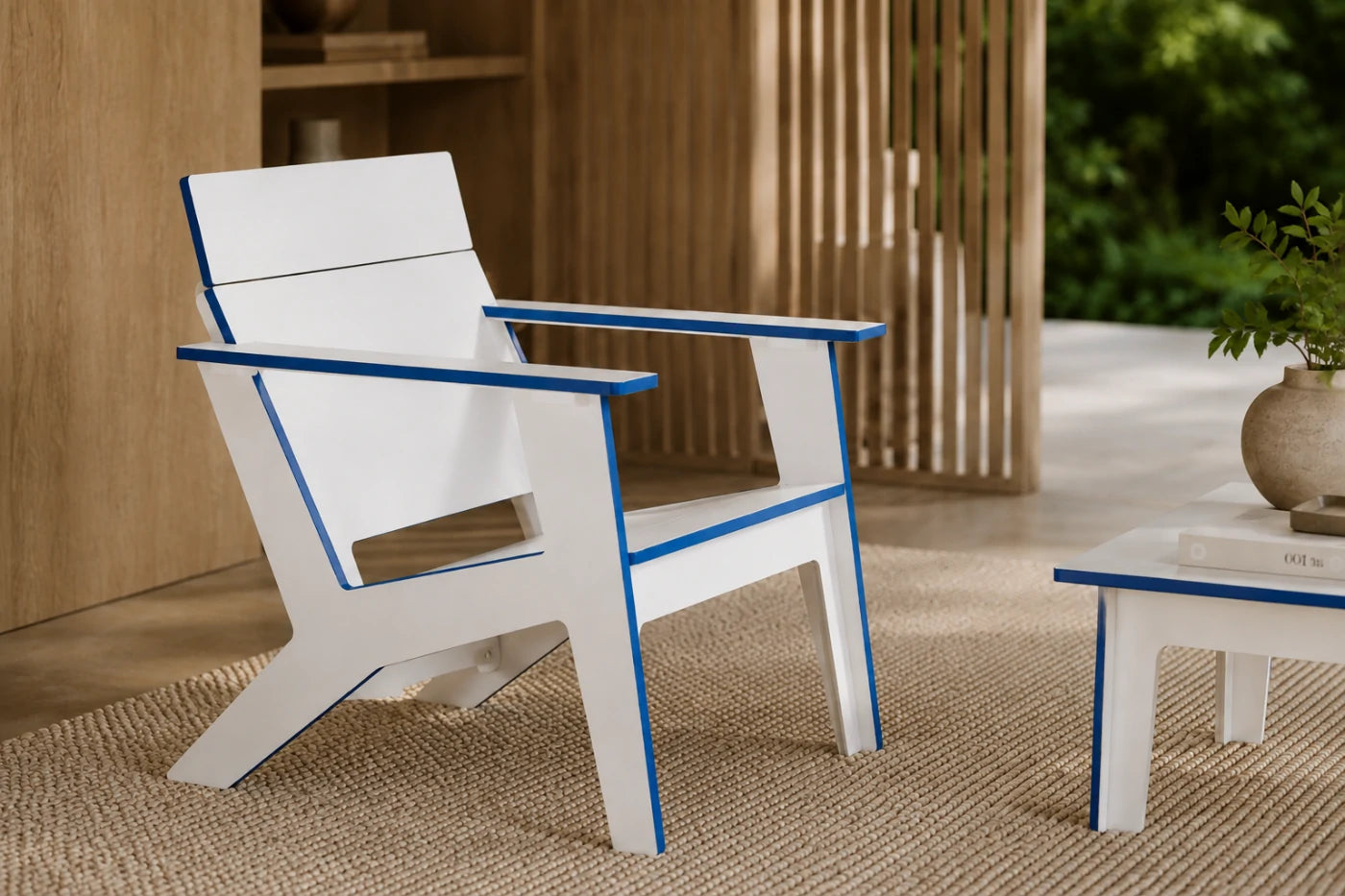 A modern white outdoor chair with blue trim details, styled on a woven jute rug next to a matching side table in a warm, sunlit patio setting.