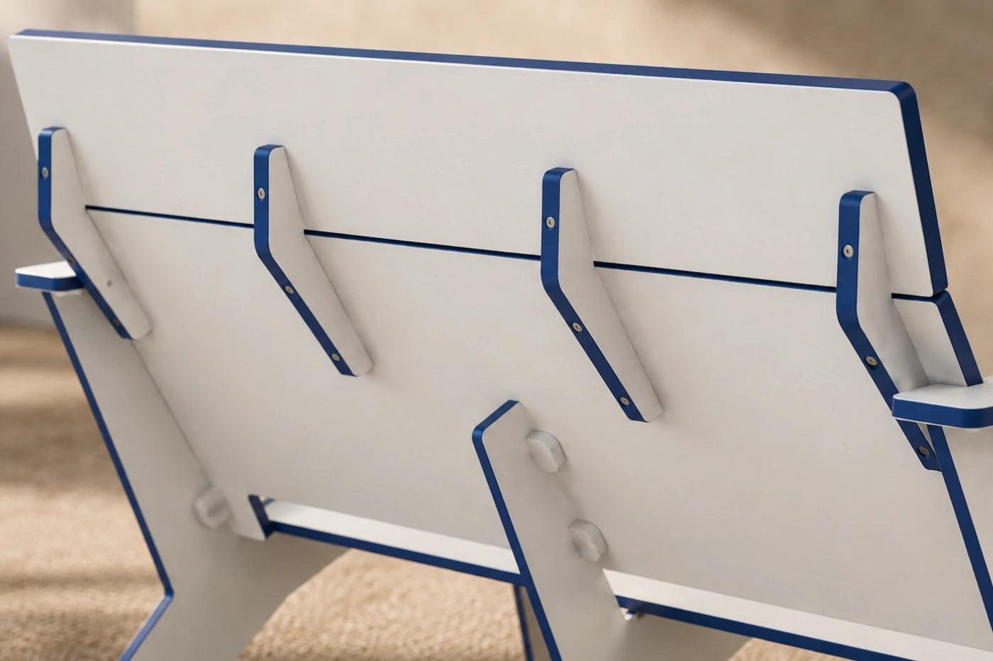 Close-up of the back of a white chair with blue trim, resting on a beige carpeted floor.