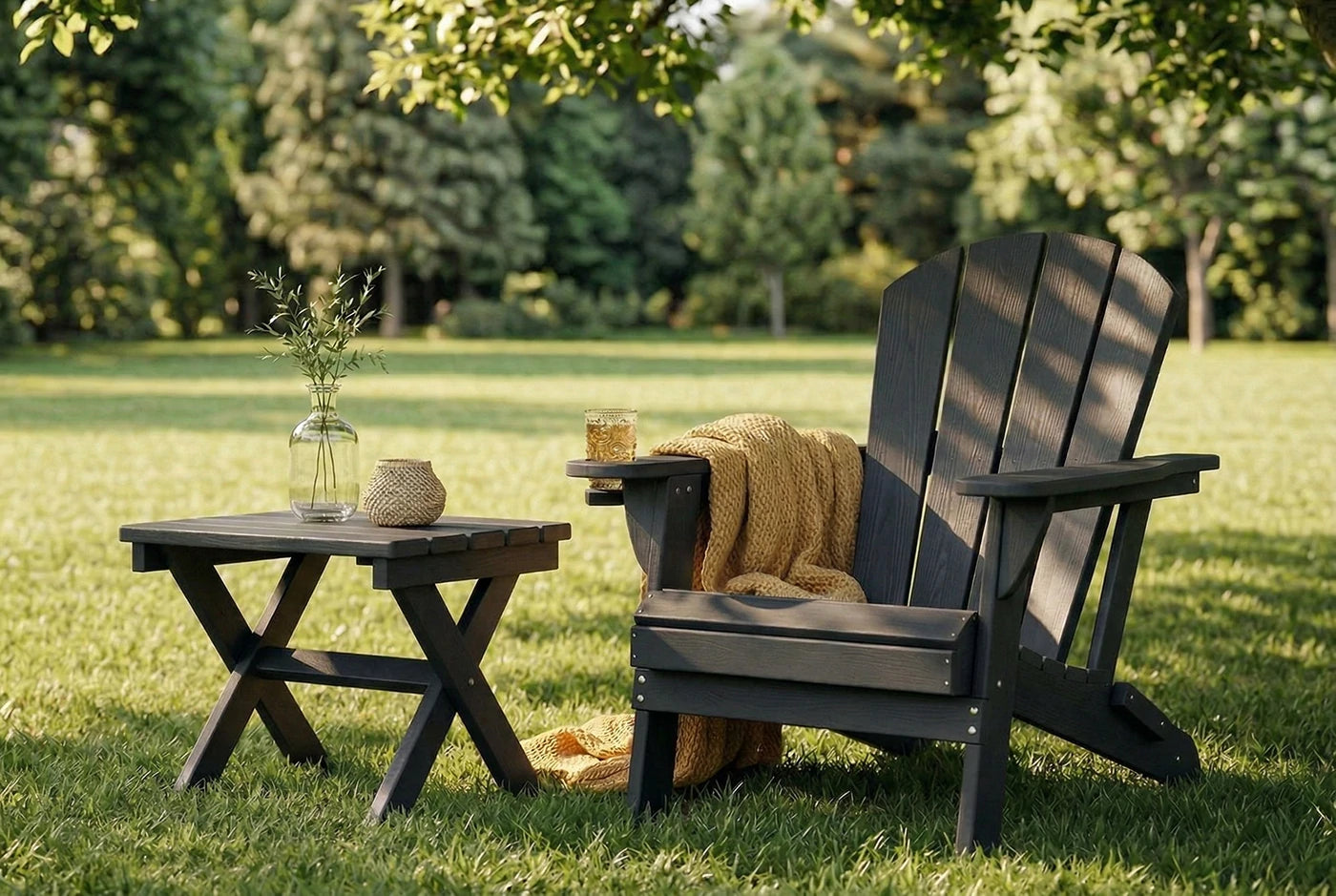 Outdoor setting with a black Adirondack chair and small table on grass
