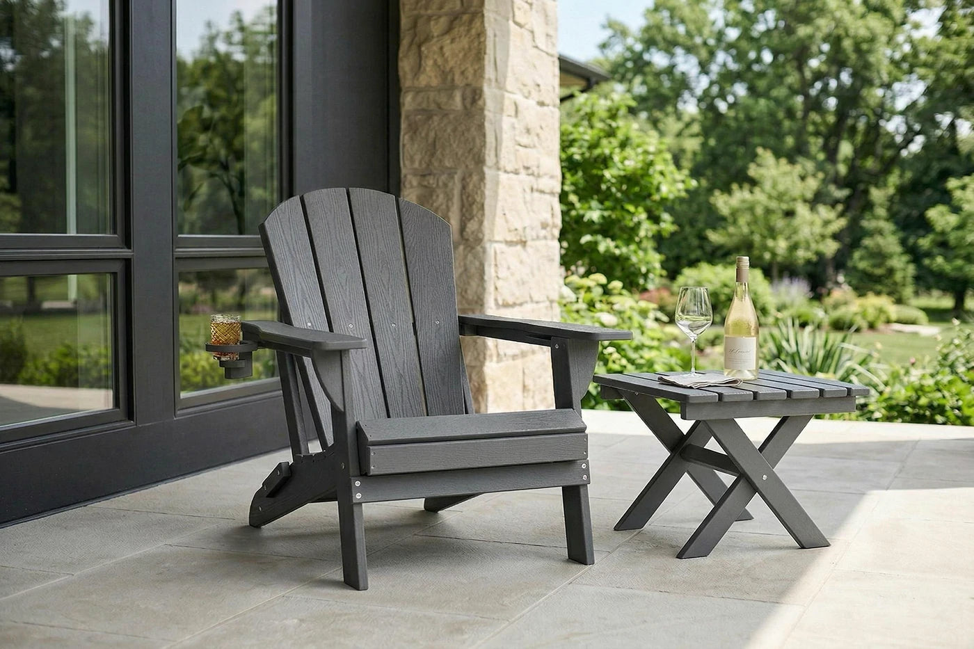Gray Adirondack chair and table set on a patio with a view of a garden.