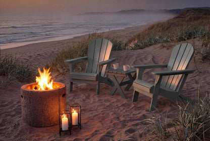 Two Adirondack chairs by a fire pit on a sandy beach at dusk.