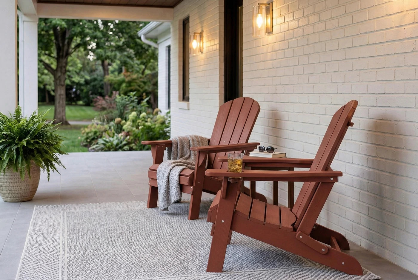 Two HDPE Adirondack chairs on a porch with a white wall and garden view.