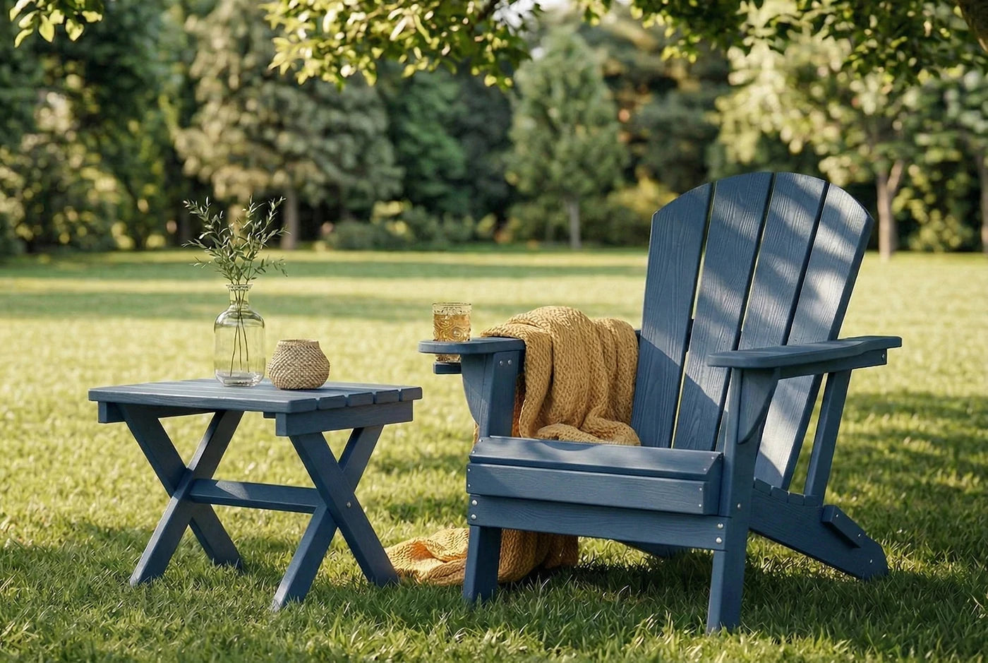 Blue Adirondack chair with a small table on a grassy lawn with trees in the background