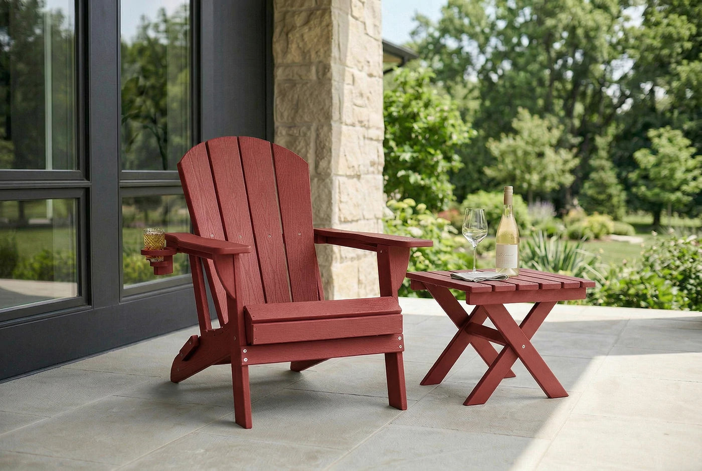 Red Adirondack chair and matching side table on a patio with a garden view.