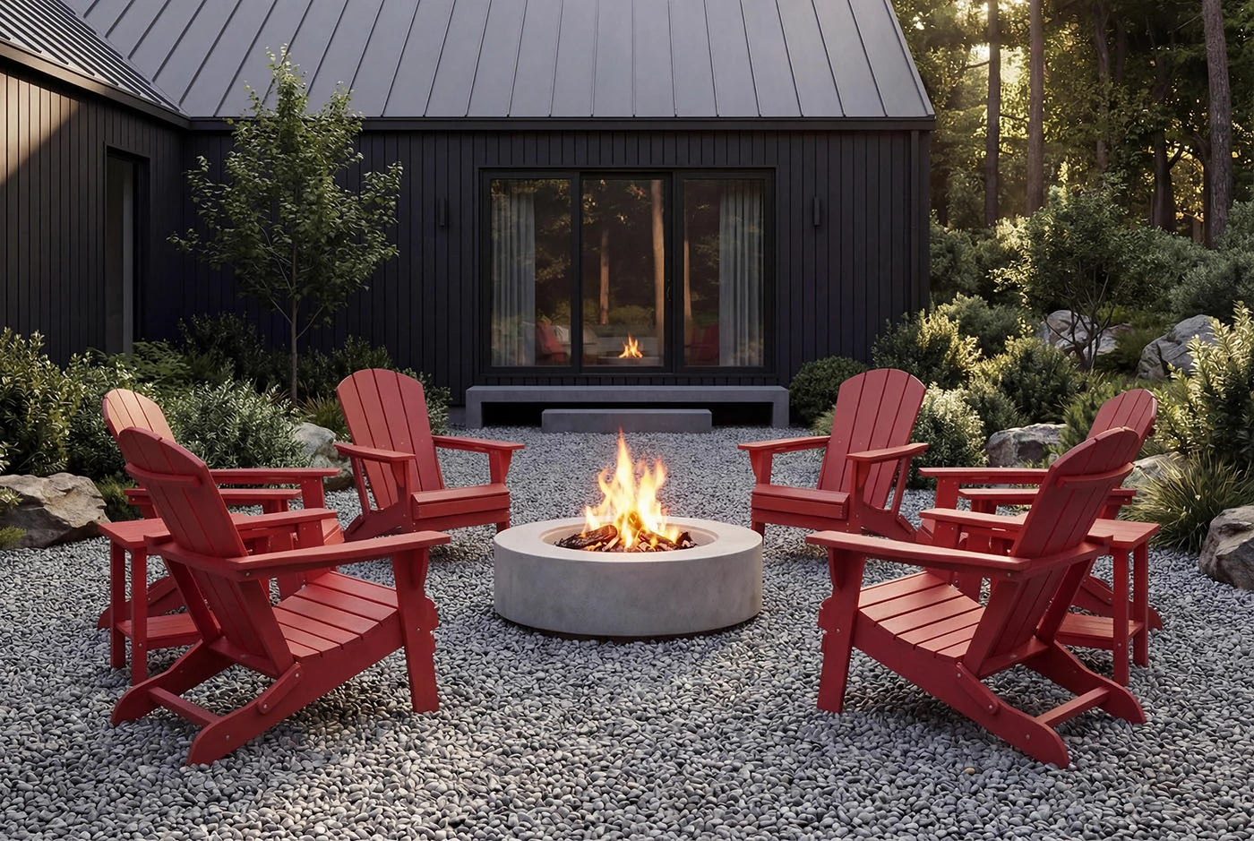 Red Adirondack chairs around a fire pit in front of a dark-colored building with large windows.