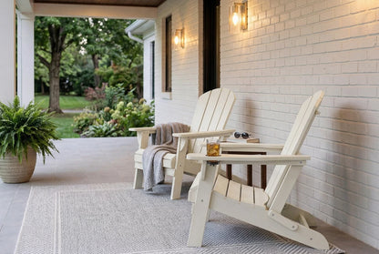 Two HDPE Adirondack chairs on a porch with a white brick wall and outdoor setting.