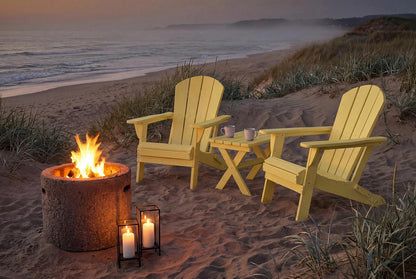 Two Adirondack chairs with a fire pit and candles on a sandy beach at dusk.