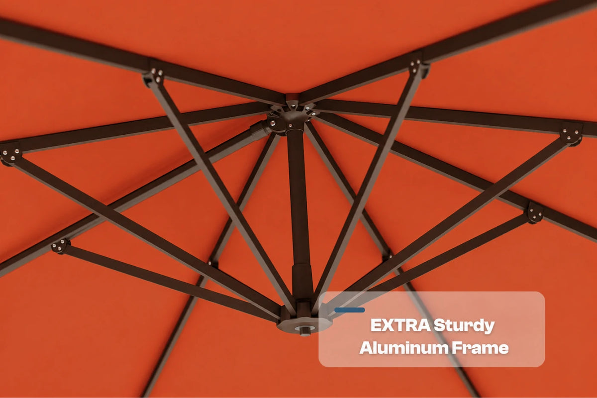 Close-up underside view of an orange patio umbrella showing the dark aluminum canopy frame structure, with a text overlay that reads 'EXTRA Sturdy Aluminum Frame'.