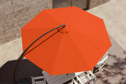 Bright orange patio umbrella with a curved black metal pole, shown from an overhead angle in an outdoor patio setting with white chairs and a stone wall background.