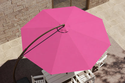 Rose pink patio umbrella with a curved black metal pole, shown from an overhead angle in an outdoor patio setting with white chairs and a stone wall background.