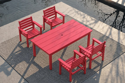 A red outdoor dining set consisting of a rectangular slatted table and four matching armchairs, arranged on a gray textured rug beside a concrete patio and reflective water.
