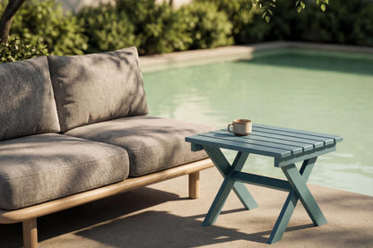 Outdoor setting with a gray sofa and a SIDE table by a pool.