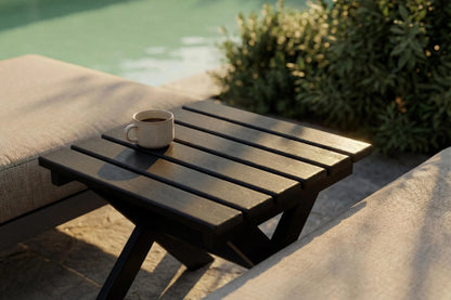 Wooden table with a cup on it by a poolside