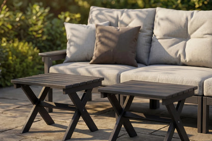 Outdoor patio set with beige cushioned sofa and two wooden side tables.