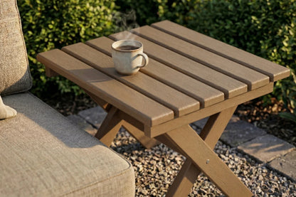 HDPE outdoor side table with a cup on it, next to a chair with a cushion.