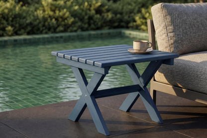 Outdoor side table with a cup and saucer next to a poolside chair.