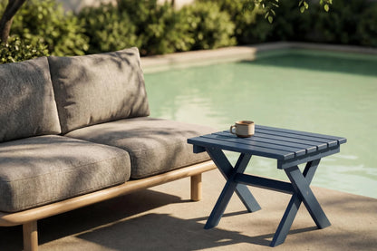 Outdoor setting with a gray sofa and small blue table by a pool