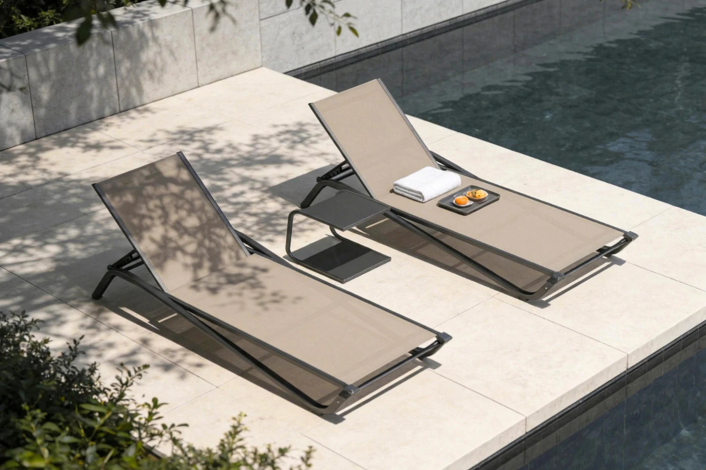 Two beige lounge chairs by a poolside with a book and small object on one of them.
