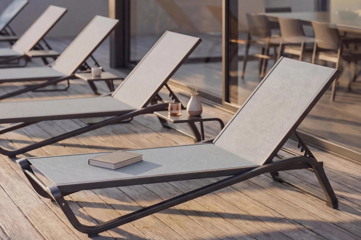 Outdoor lounge chairs on a wooden deck with a book and small table.