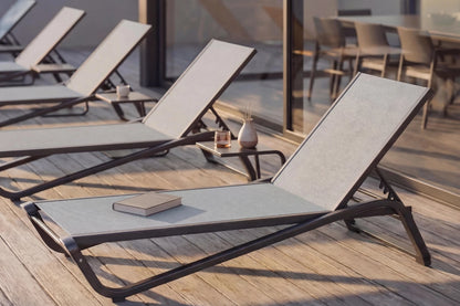 Outdoor lounge chairs on a wooden deck with a book and small table.