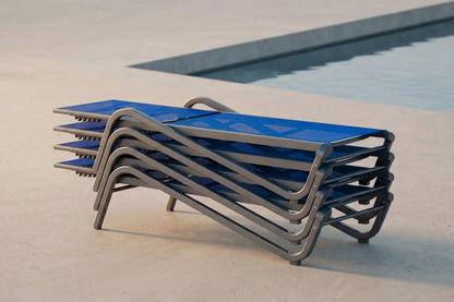 Stack of blue lounge chairs with metal frames near a pool
