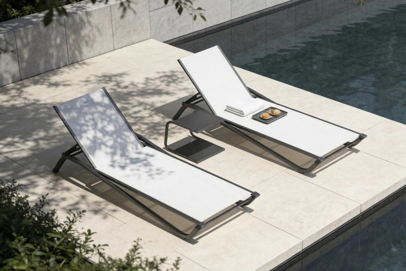 Two white lounge chairs on a patio next to a pool.