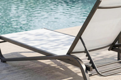 Chaise lounge chair by a pool with water in the background
