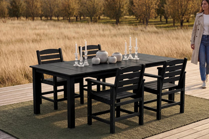 Black outdoor dining set with chairs on a wooden deck, woman walking in the background.