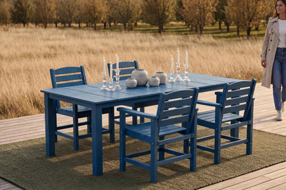 Blue outdoor dining set with chairs on a wooden deck, woman walking in the background.