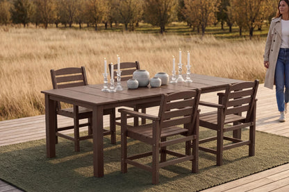 Outdoor dining set with table and chairs on a wooden deck, woman walking in the background.